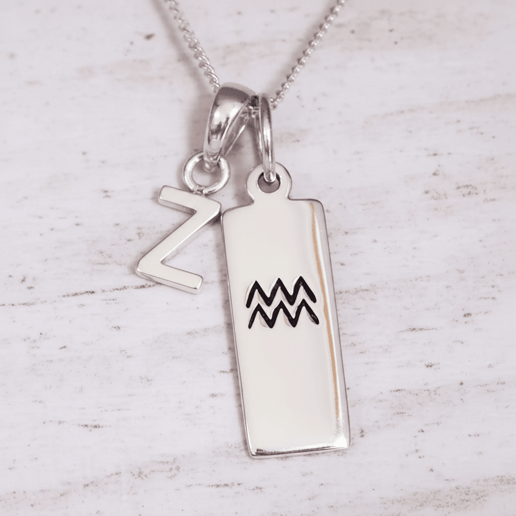 Silver pendant with 'Z' and Aquarius symbol on a light wooden background