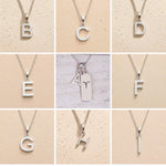 Collage of silver necklaces with letter pendants A to I on a beige background as personalised initials to add to the Aries Zodiac Necklace