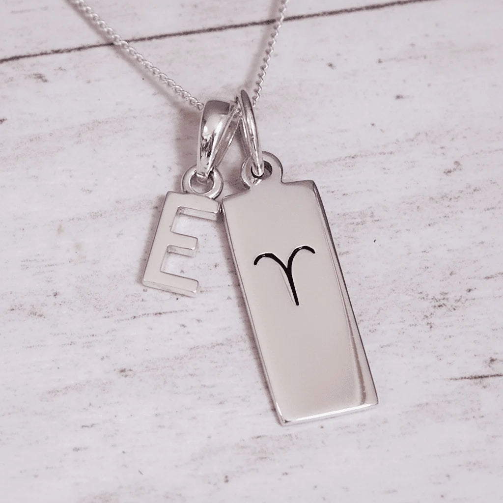 Sterling Silver necklace with a 'E' initial pendant and a Aries Zodiac pendant on a light grey background.