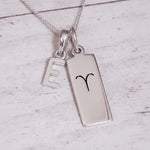 Sterling Silver necklace with a 'E' initial pendant and a Aries Zodiac pendant on a light grey background.