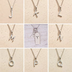 Collage of silver necklaces with letter pendants J to Q on a beige background as personalised initials to add to the Aries Zodiac Necklace