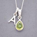 sterling Silver double pendant necklace with a green teardrop august birthstone peridot pendant and letter 'A' charm on a grey background