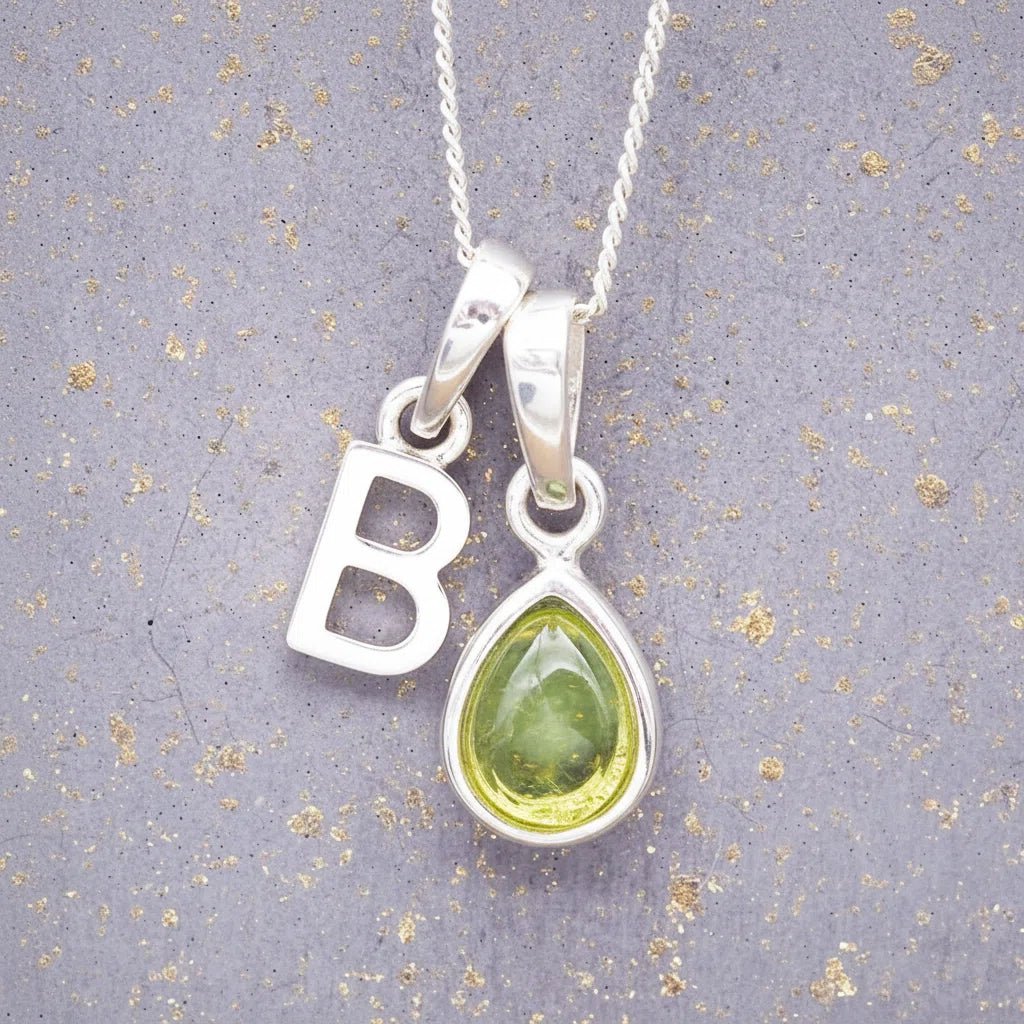 Sterling Silver 'B' Initial Necklace with a pear-shaped cabochon August Birthstone Peridot Pendant on a grey background