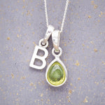 Sterling Silver 'B' Initial Necklace with a pear-shaped cabochon August Birthstone Peridot Pendant on a grey background