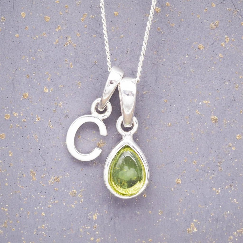 Sterling Silver 'C' Initial Necklace with a pear-shaped cabochon August Birthstone Peridot Pendant on a grey background