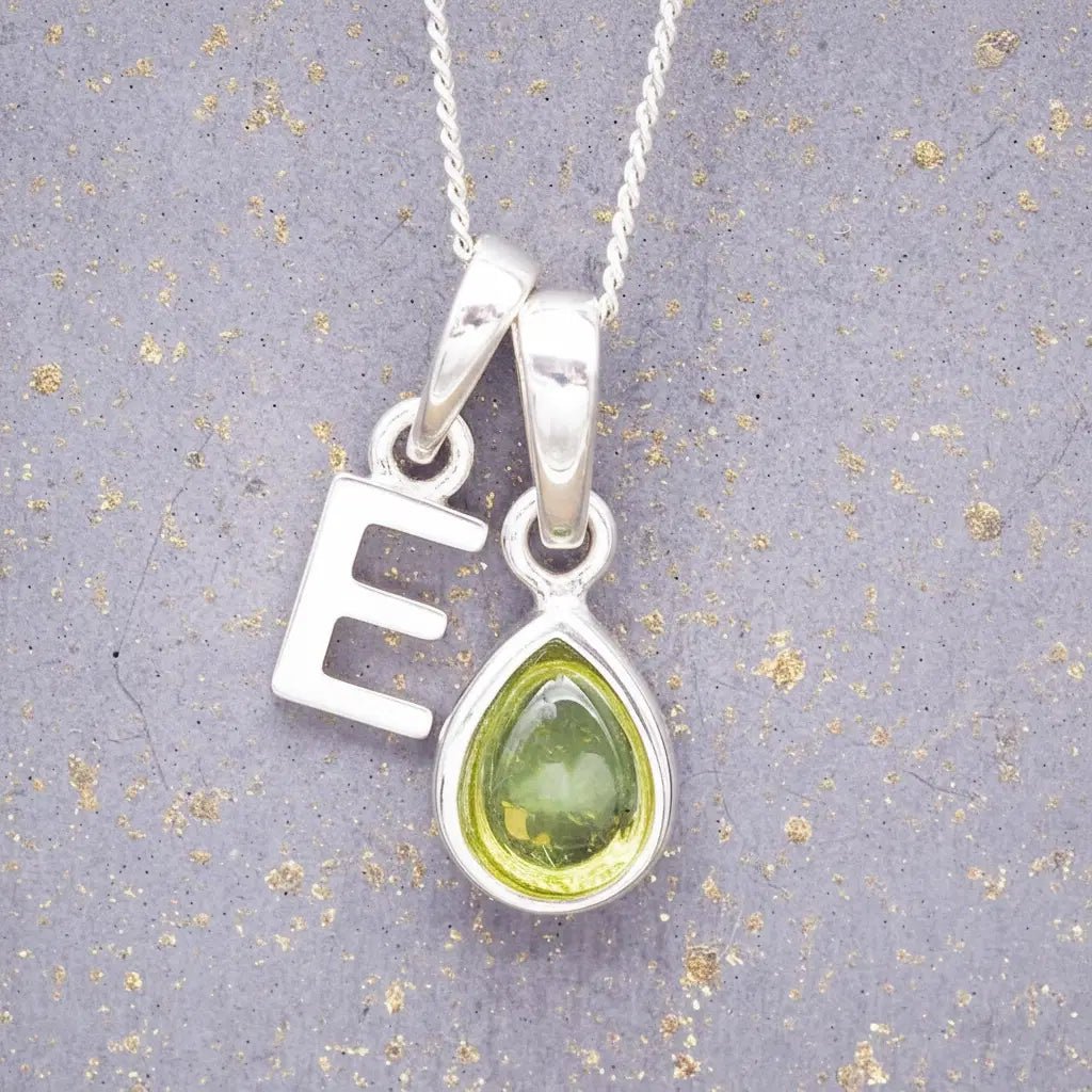 Sterling Silver 'E' Initial Necklace with a pear-shaped cabochon August Birthstone Peridot Pendant on a grey background