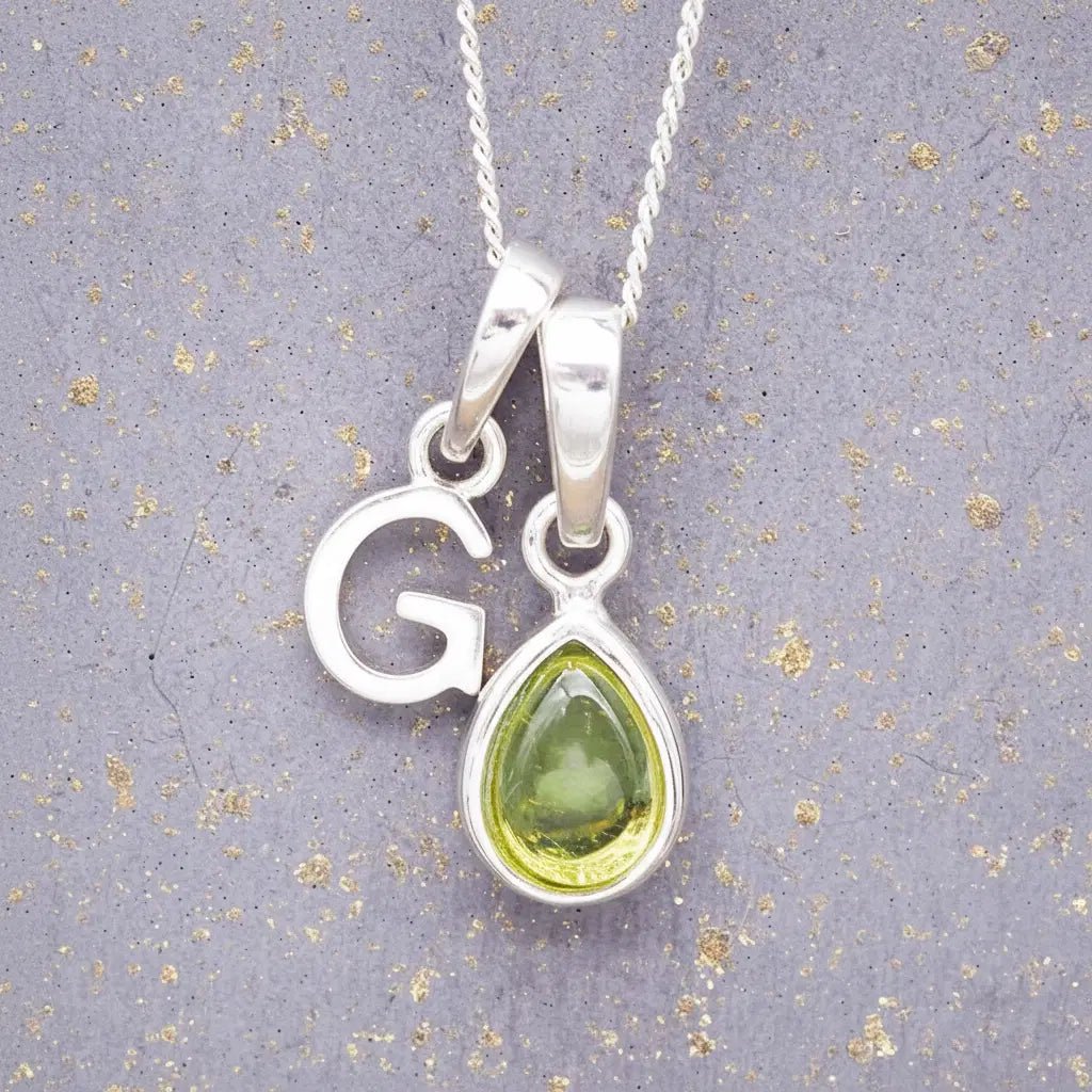 Sterling Silver 'G' Initial Necklace with a pear-shaped cabochon August Birthstone Peridot Pendant on a grey background
