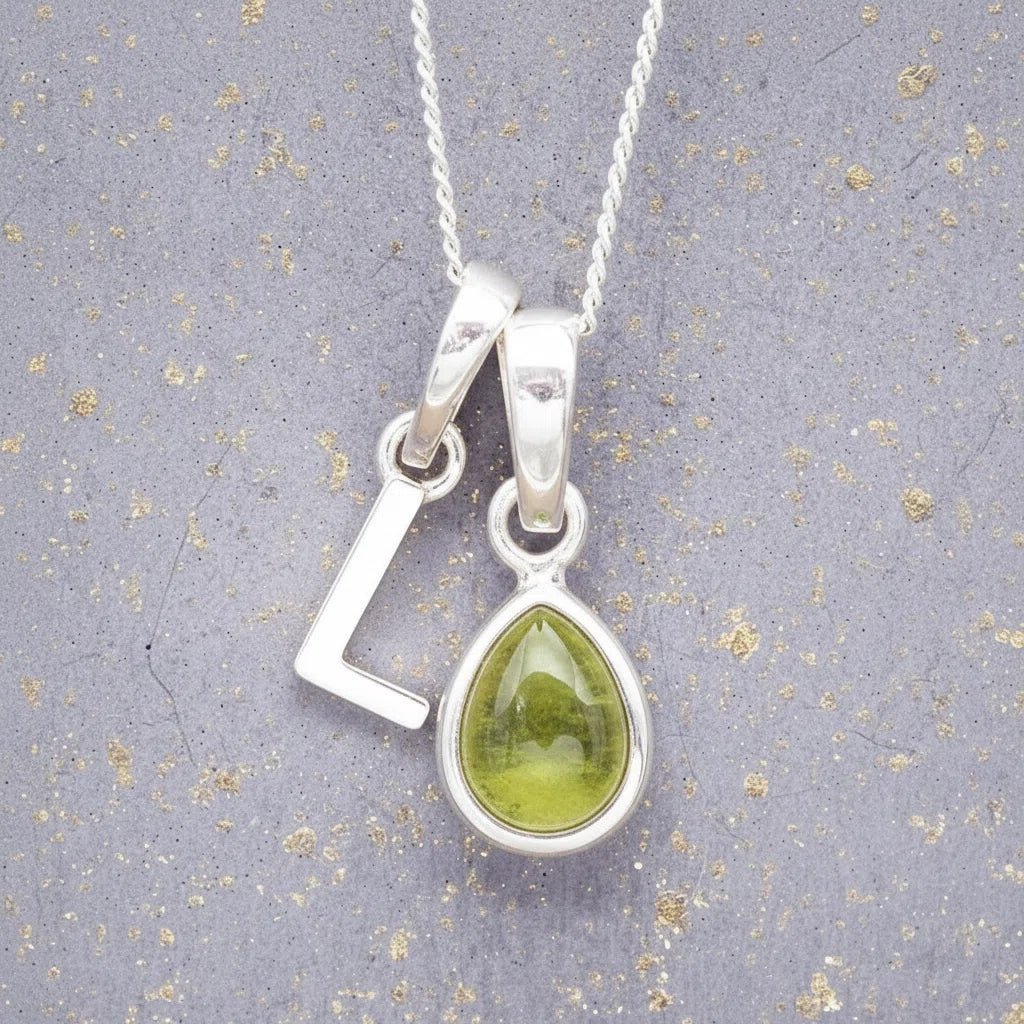 Sterling Silver 'L' Initial Necklace with a pear-shaped cabochon August Birthstone Peridot Pendant on a grey background