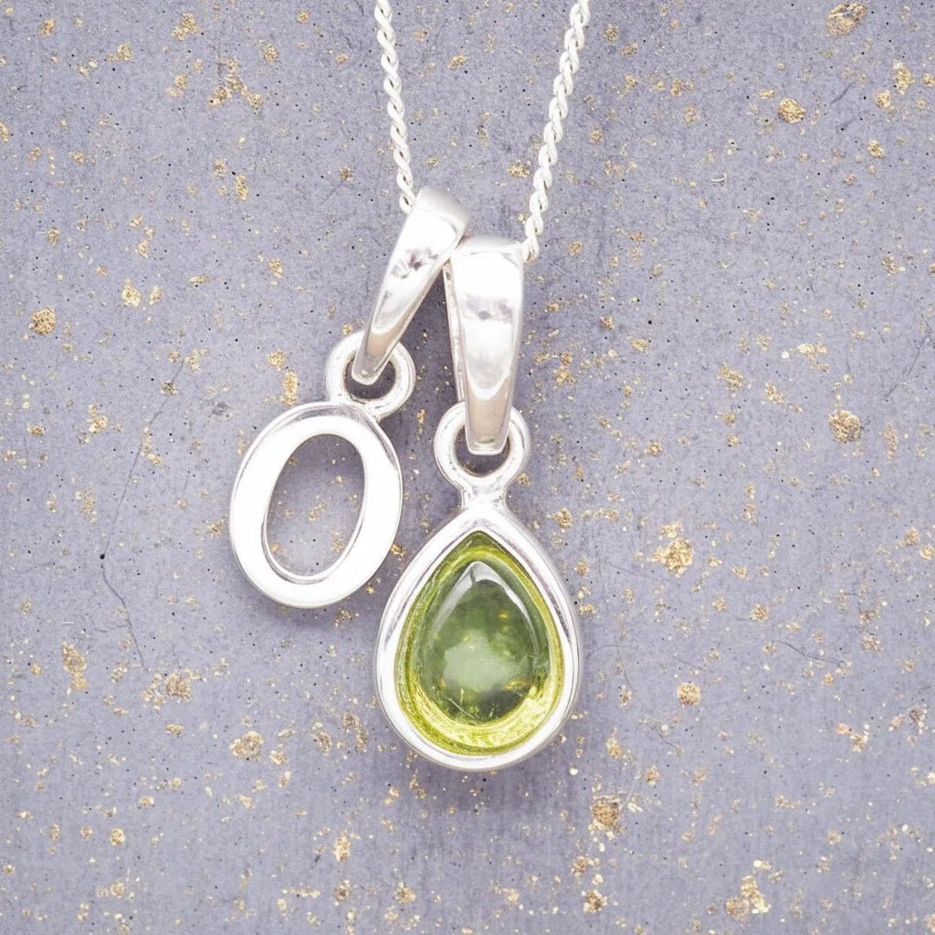 Sterling Silver 'O' Initial Necklace with a pear-shaped cabochon August Birthstone Peridot Pendant on a grey background
