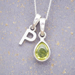 Sterling Silver 'P' Initial Necklace with a pear-shaped cabochon August Birthstone Peridot Pendant on a grey background