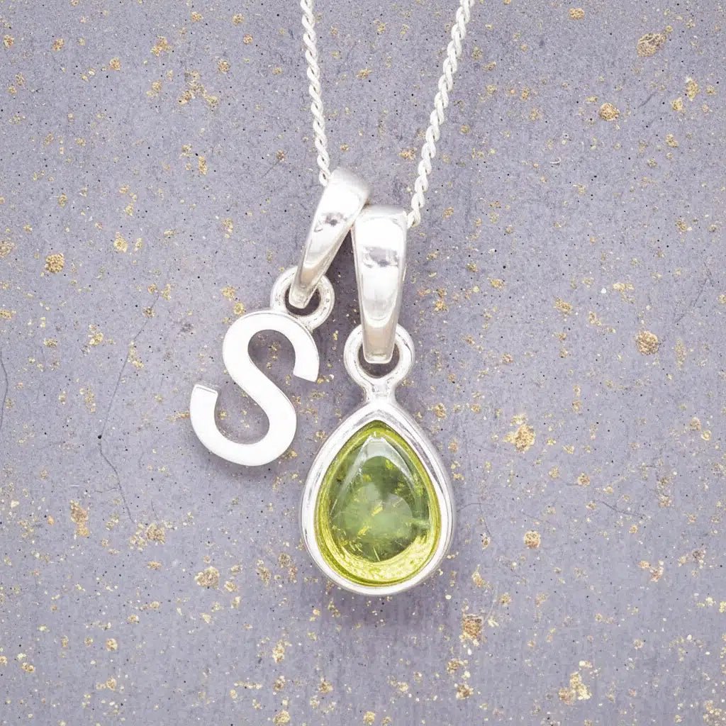 Sterling Silver 'S' Initial Necklace with a pear-shaped cabochon August Birthstone Peridot Pendant on a grey background