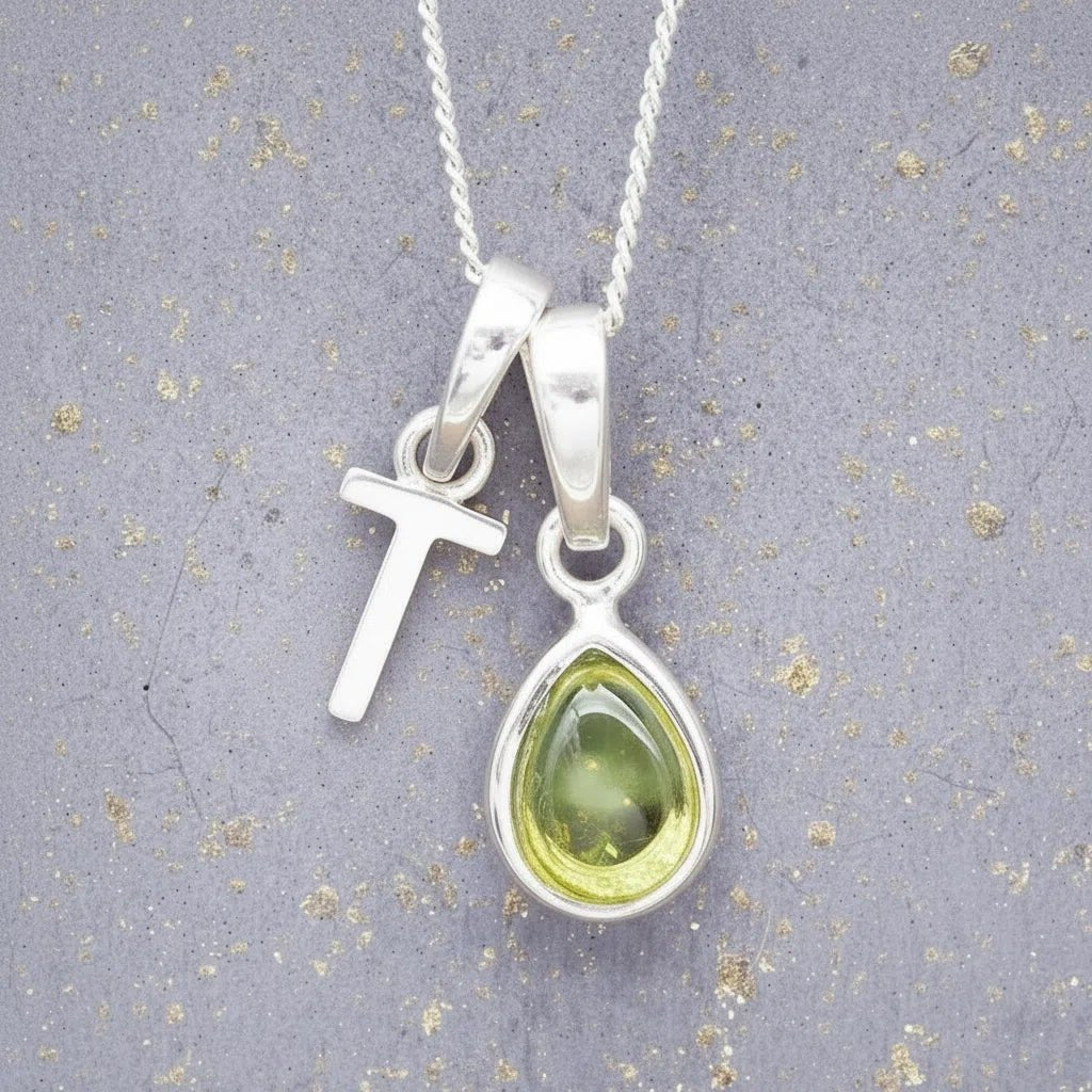 Sterling Silver 'T' Initial Necklace with a pear-shaped cabochon August Birthstone Peridot Pendant on a grey background