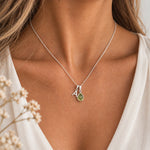Model wearing a sterling silver initial A and natural August peridot necklace with a soft ivory blouse