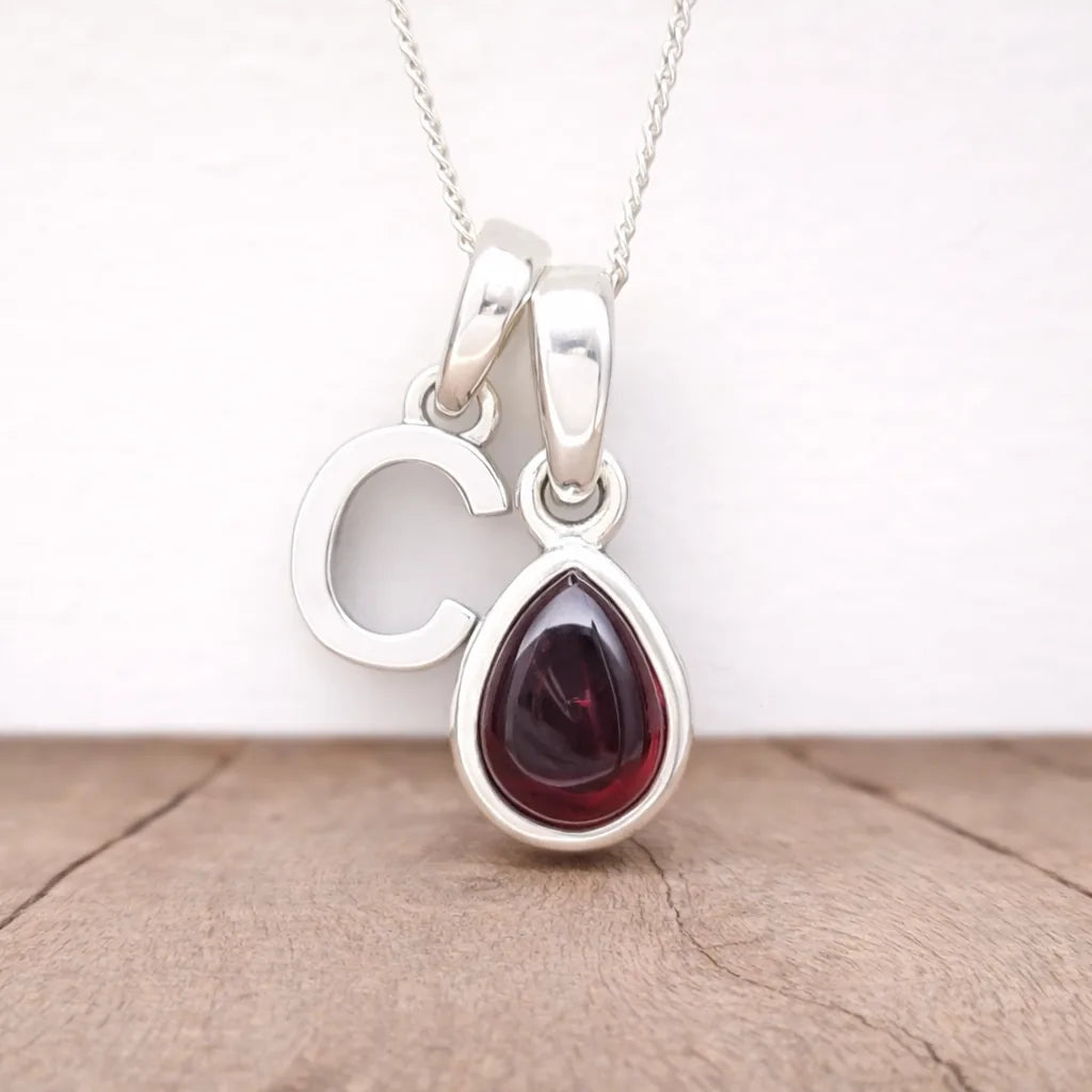 Silver Initial C pendant with a teardrop-shaped red garnet gemstone on a white background