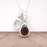 Silver Initial C pendant with a teardrop-shaped red garnet gemstone on a white background