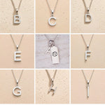 Silver letter pendants from B to H on a beige background as personalised letter options for the Cancer Zodiac Necklace
