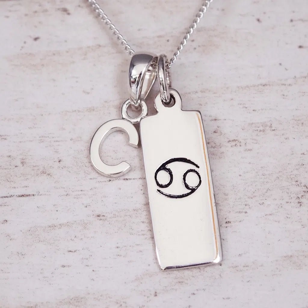 Indie and Harper personalised silver Cancer zodiac necklace with a hand-carved star sign symbol and 'C'initial charm on a 925 sterling silver necklace chain