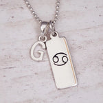 Sterling Silver necklace with 'G' initial pendant and Cancer Zodiac pendant on a textured grey background.