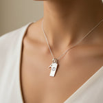 Sterling Silver necklace with a initial pendant and a cancer zodiac pendant on a person wearing a white top