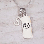 Sterling Silver necklace with 'S' initial pendant and Cancer Zodiac pendant on a textured grey background.
