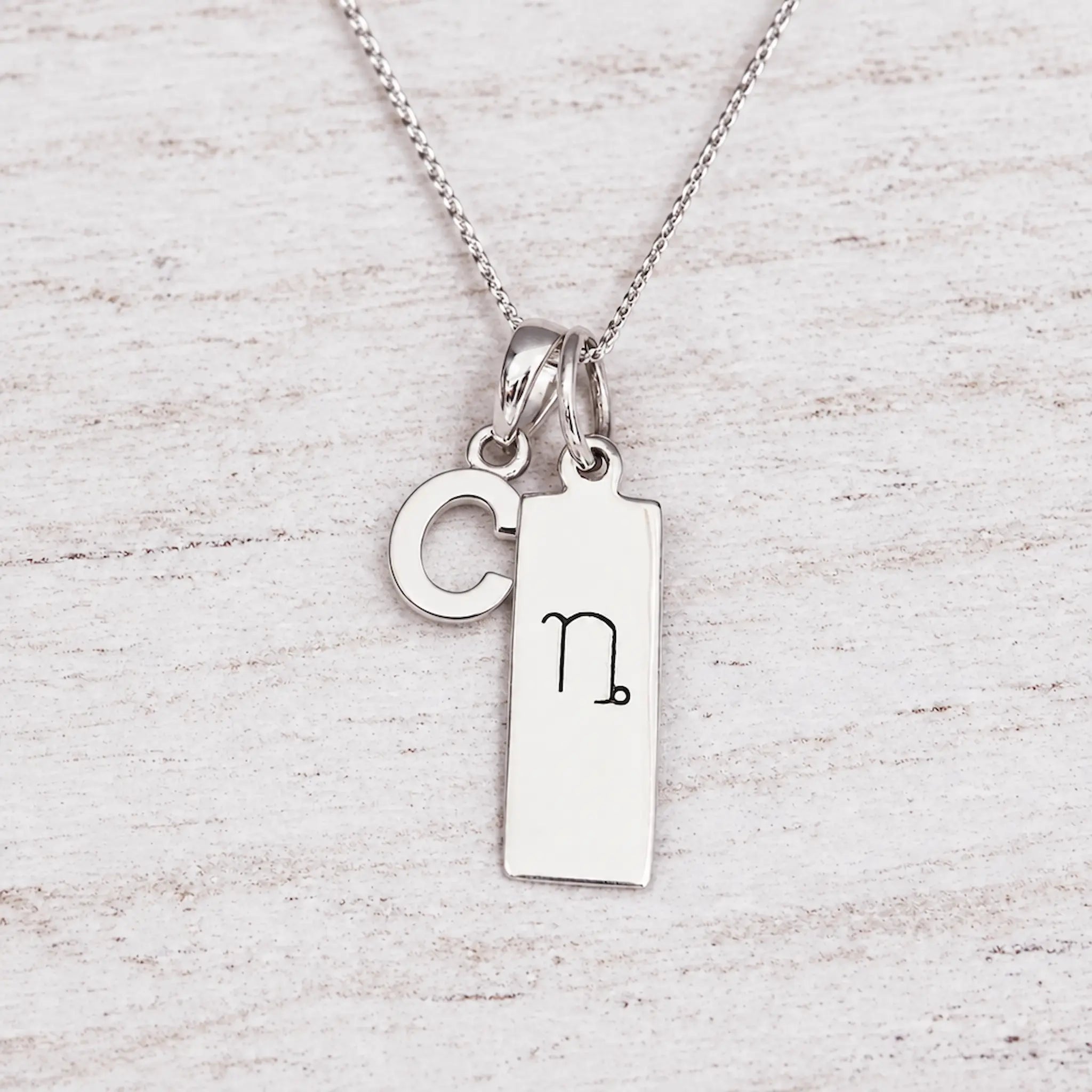 Silver Initial and Capricorn Zodiac Necklace with sterling silver letter C pendant on light wood