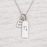 Silver Initial and Capricorn Zodiac Necklace with sterling silver letter E pendant on light wood