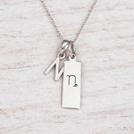 Silver Initial and Capricorn Zodiac Necklace with sterling silver letter N pendant on light wood