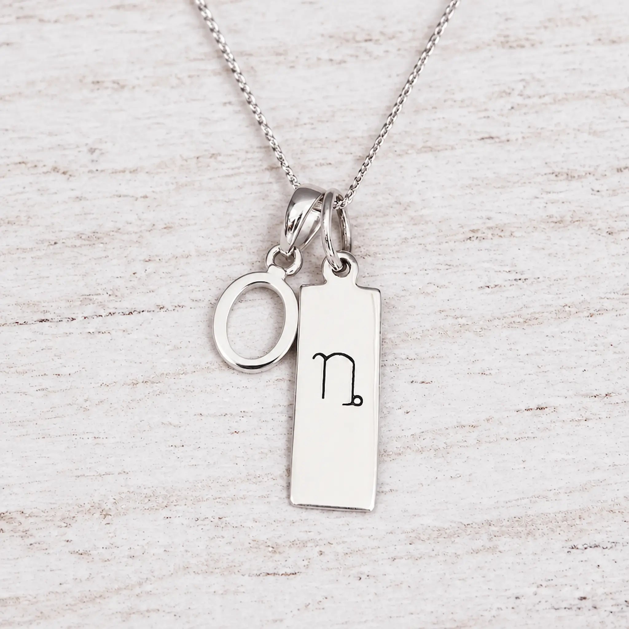 Silver Initial and Capricorn Zodiac Necklace with sterling silver letter O pendant on light wood
