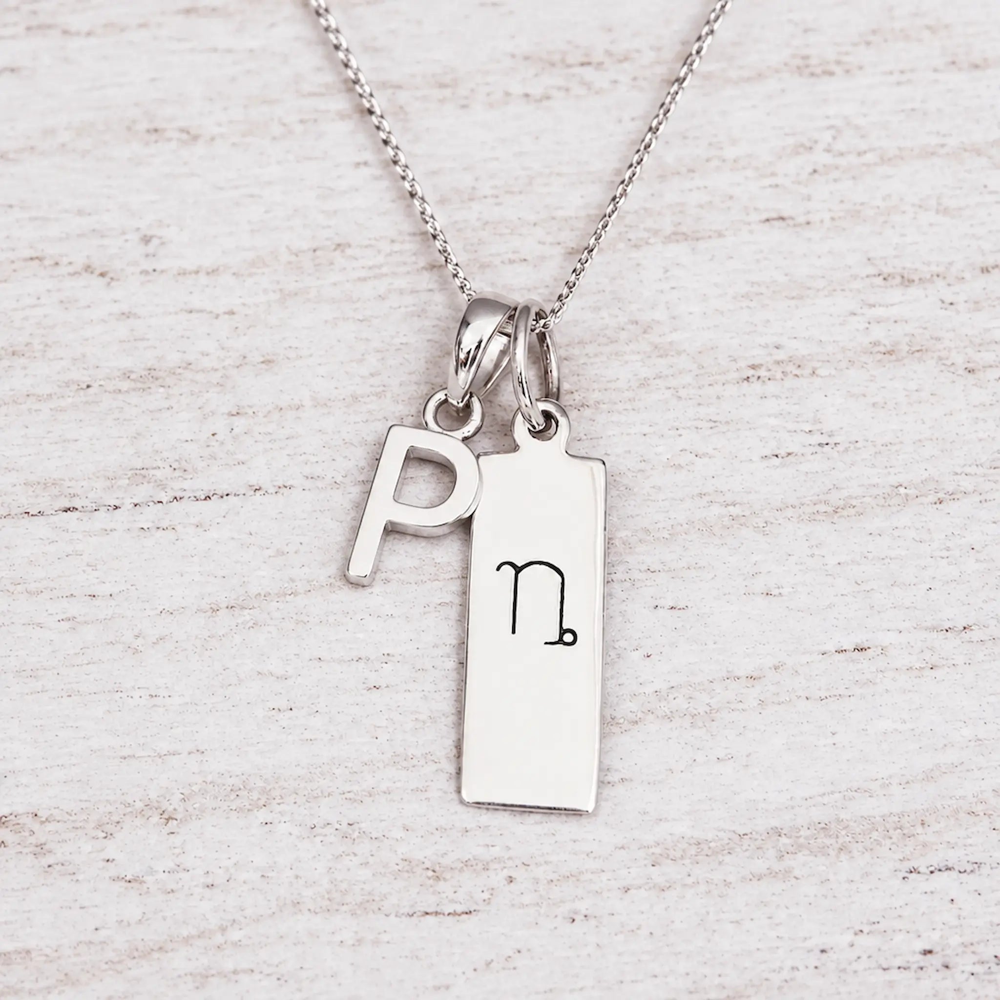 Silver Initial and Capricorn Zodiac Necklace with sterling silver letter P pendant on light wood