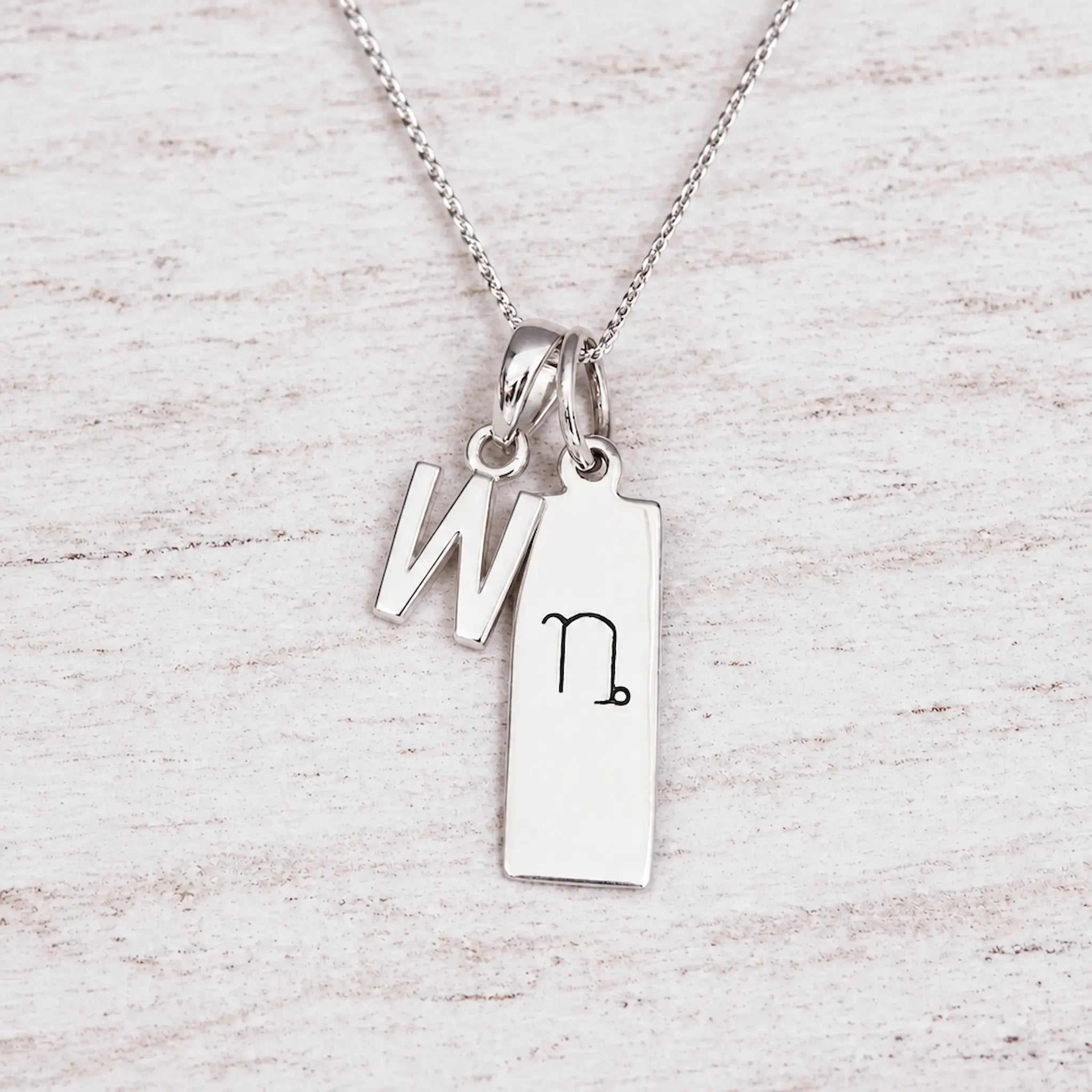 Silver Initial and Capricorn Zodiac Necklace with sterling silver letter W pendant on light wood