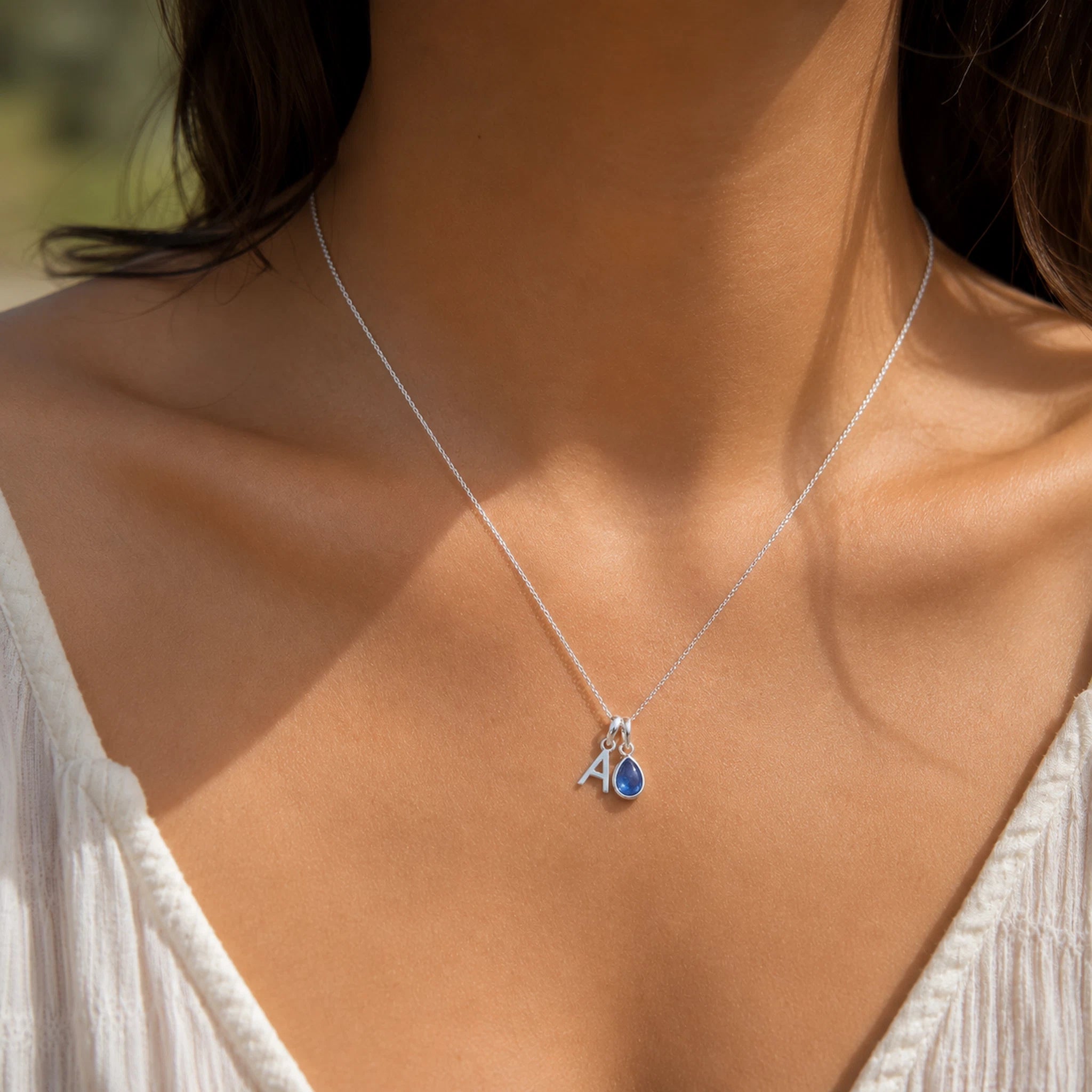 sterling silver necklace with an initial A pendant and teardrop December Birthstone Tanzanite Necklace worn on a person