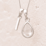 sterling Silver necklace with a 'I' initial pendant and pear shaped herkimer quartz pendant on a light beige background