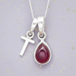 Sterling Silver necklace with 'T' initial pendant and July Birthstone Ruby gemstone pear-shaped pendant on a grey background.