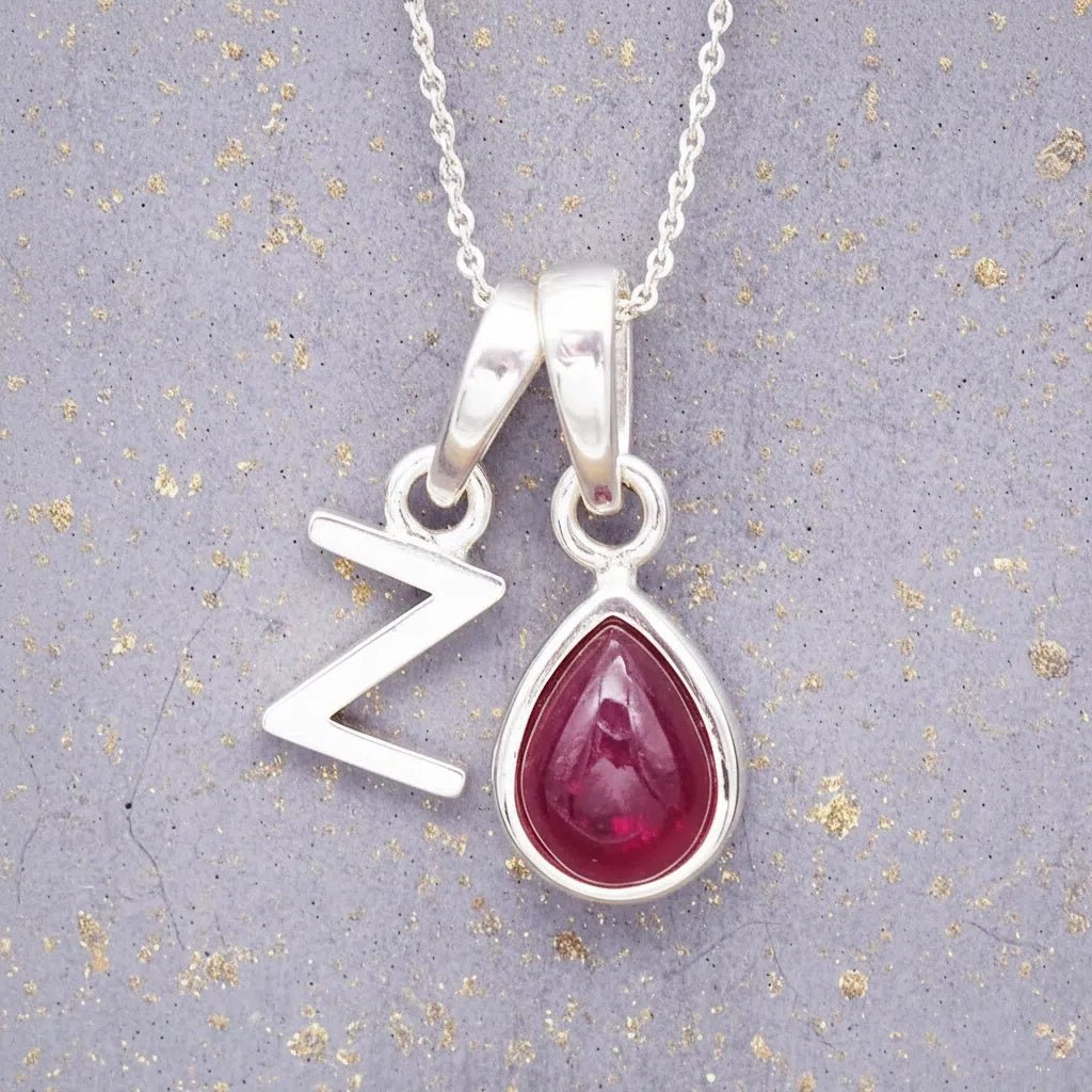 Sterling Silver necklace with 'Z initial pendant and July Birthstone Ruby gemstone pear-shaped pendant on a grey background.