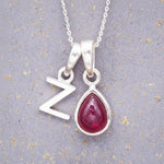 Sterling Silver necklace with 'Z initial pendant and July Birthstone Ruby gemstone pear-shaped pendant on a grey background.