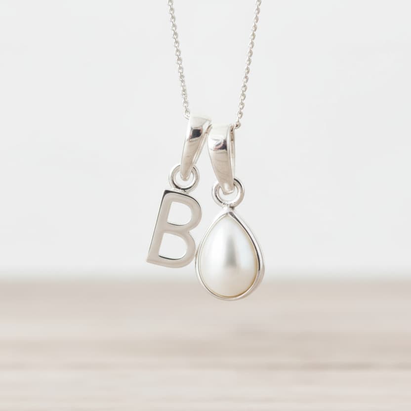 Sterling Silver necklace with 'B' initial pendant and teardrop-shaped June Birthstone mother of pearl pendant on a light background