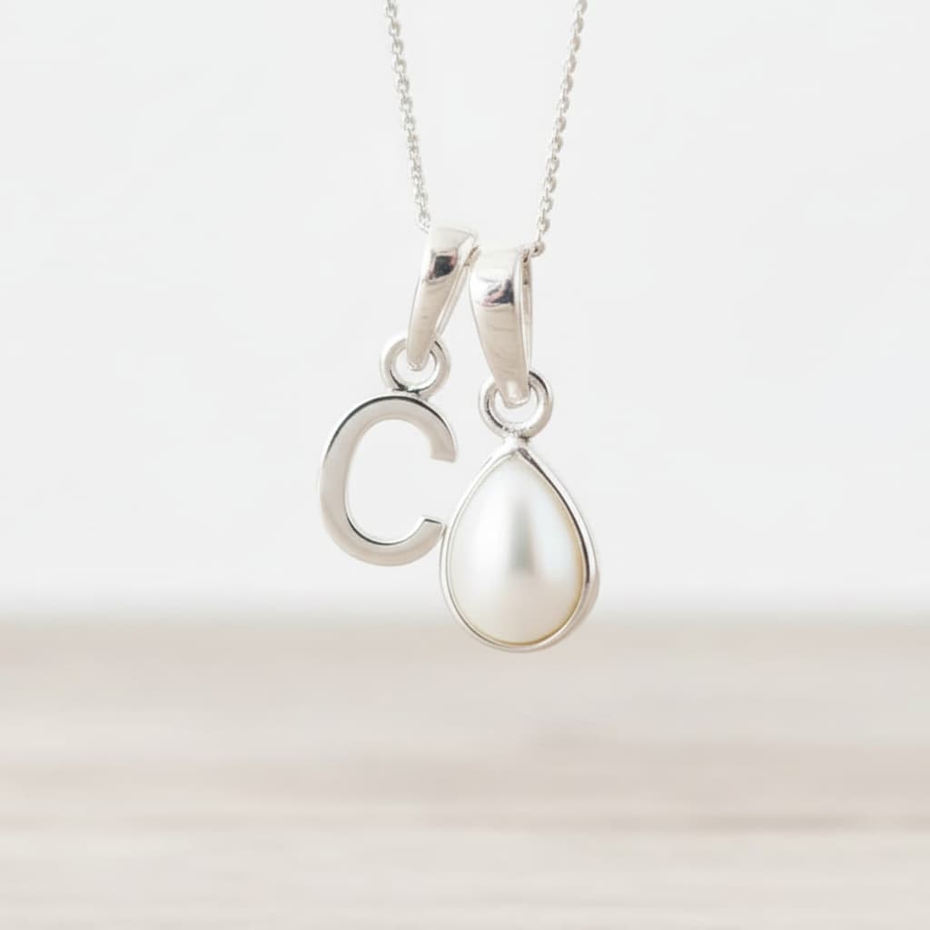 Sterling Silver necklace with 'C' initial pendant and teardrop-shaped June birthstone mother of pearl pendant on a light background