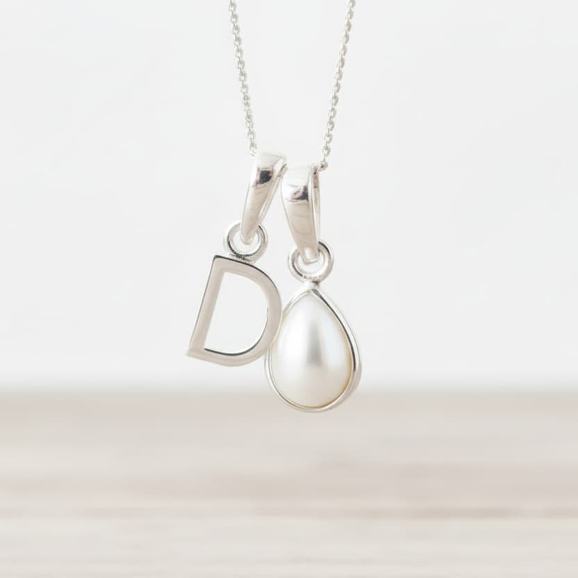 Sterling Silver necklace with 'D' initial pendant and teardrop-shaped June Birthstone mother of pearl pendant on a light background