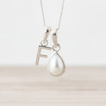 Sterling Silver June birthstone necklace with a pear-shaped natural mother of pearl pendant and letter 'F' charm.
