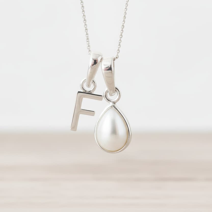 Sterling Silver June birthstone necklace with a pear-shaped natural mother of pearl pendant and letter 'F' charm.