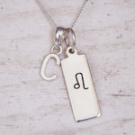 Sterling Silver necklace with a Leo Zodiac Star Sign pendant and a initial 'C' letter pendant on a light wooden background.