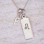 Sterling Silver necklace with a Leo Zodiac Star Sign pendant and a initial 'F' letter pendant on a light wooden background.