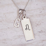 Sterling Silver necklace with a Leo Zodiac Star Sign pendant and a initial 'G' letter pendant on a light wooden background.