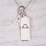 sterling Silver necklace with a libra zodiac pendant and a 'A' initial pendant on a light wooden background