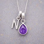 sterling Silver necklace with a purple teardrop february birthstone amethyst pendant and letter 'N' charm on a textured grey background.