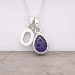 Silver initial O necklace with a purple teardrop amethyst pendant on a light wooden surface.