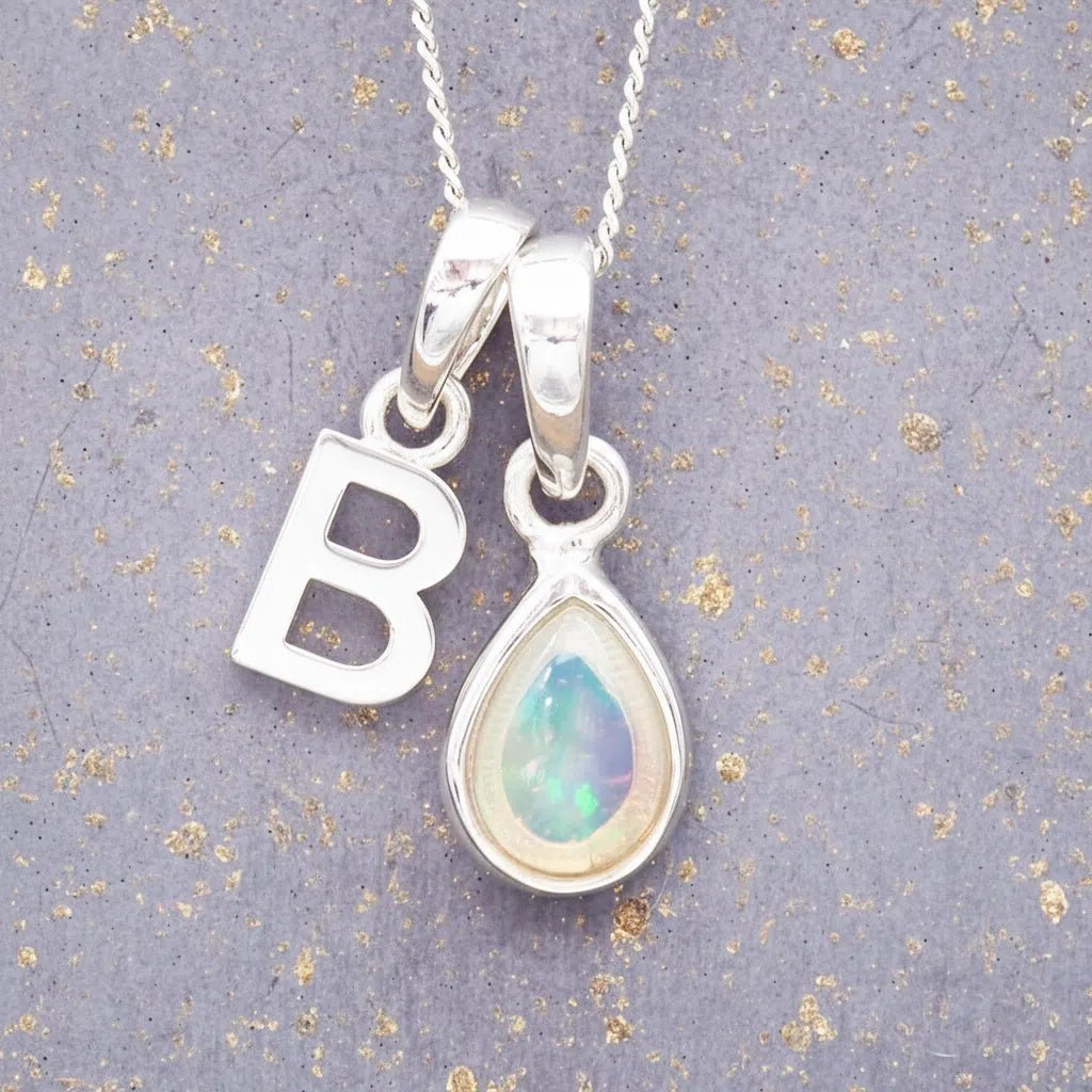 Sterling Silver necklace with 'B' initial pendant and pear-shaped October Birthstone Opal gemstone on a grey background.