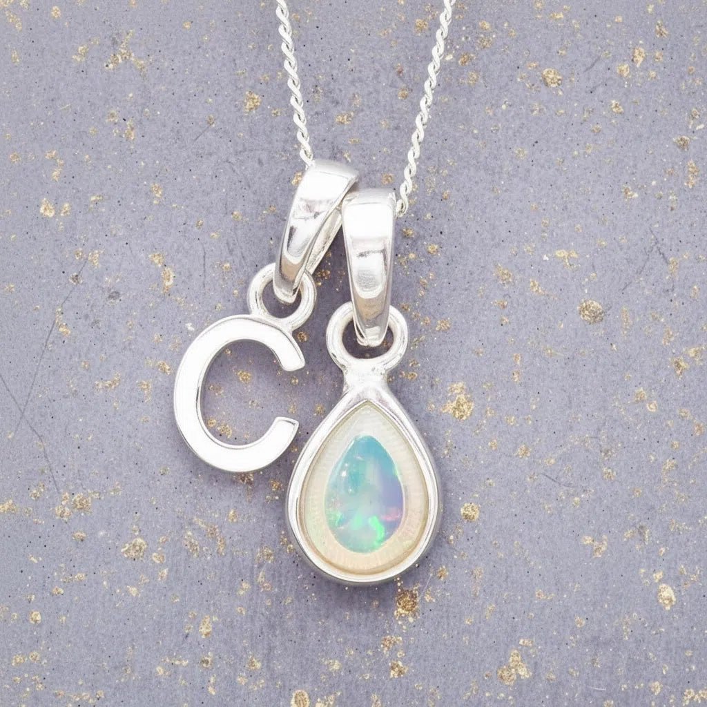 Sterling Silver necklace with 'C' initial pendant and pear-shaped October Birthstone Opal gemstone on a grey background.