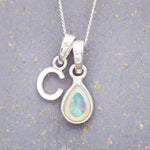 Sterling Silver necklace with 'C' initial pendant and pear-shaped October Birthstone Opal gemstone on a grey background.