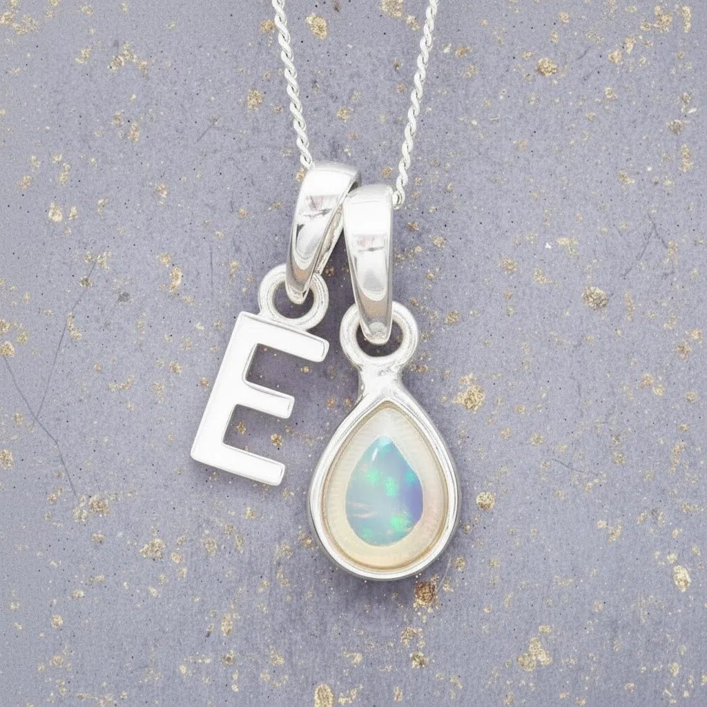 Sterling Silver necklace with 'E' initial pendant and white teardrop October Birthstone Opal gemstone on a grey background.